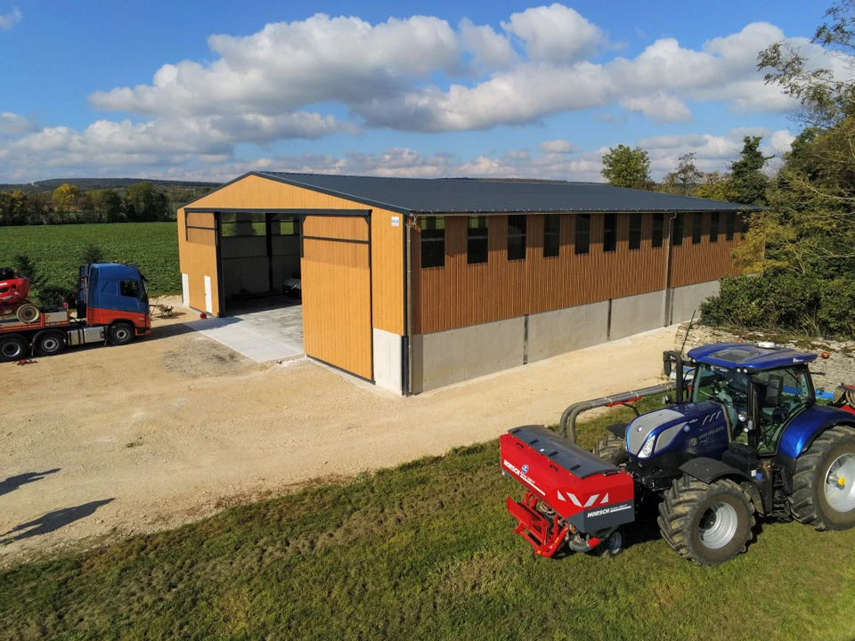 Chantier de construction ext&eacute;rieur avec une charpente m&eacute;tallique en cours d'assemblage, montrant des profil&eacute;s d'acier et des structures m&eacute;talliques en place. On voit des ouvriers en tenue de chantier et &eacute;quipement de s&eacute;curit&eacute; travaillant &agrave; la mise en place des &eacute;l&eacute;ments m&eacute;talliques, avec des liaisons boulonn&eacute;es visibles. L'image doit montrer clairement un travail de construction m&eacute;tallique professionnel et de qualit&eacute;.