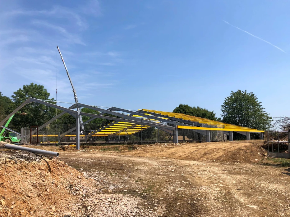Chantier de construction en extérieur avec ouvriers en silhouette travaillant sur échafaudage métallique modulaire contre ciel bleu