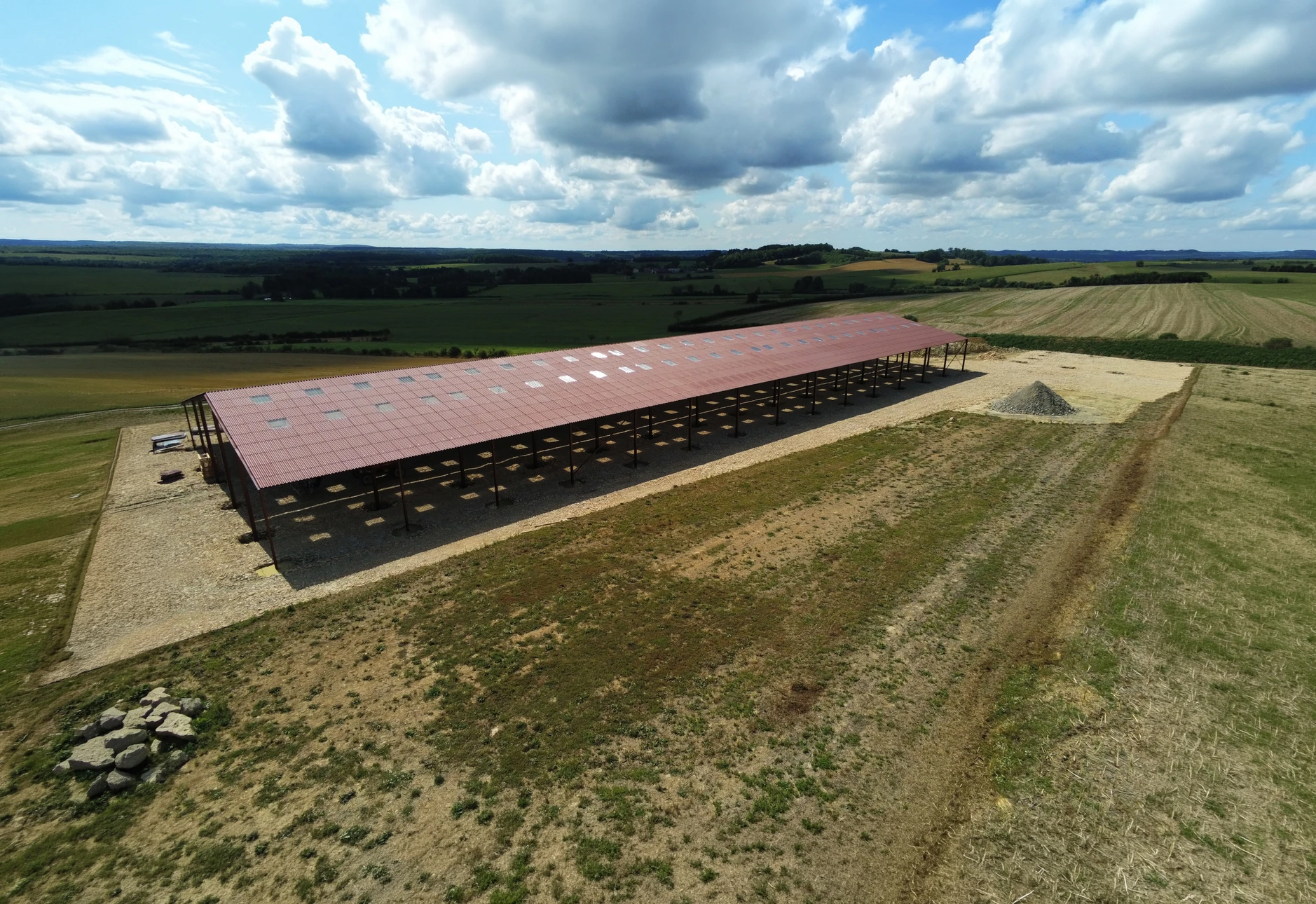 Structure métallique industrielle de type hangar ouvert, sans murs, avec toiture en bac acier nervuré sur charpente métallique peinte en rouge brun